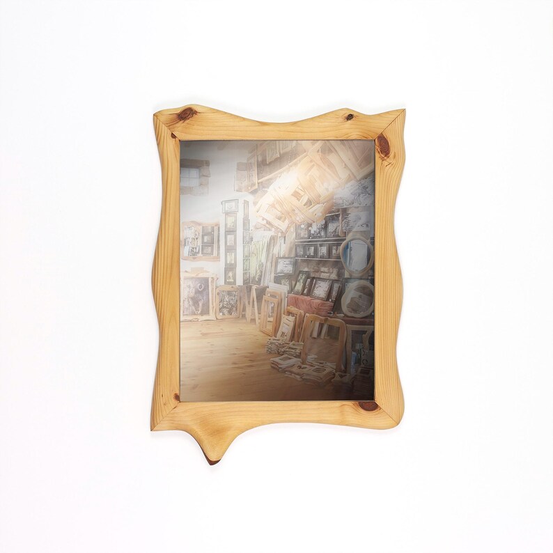 Peut inclure: Un miroir encadr&eacute; de bois clair, de forme organique et irr&eacute;guli&egrave;re. Le miroir refl&egrave;te une pi&egrave;ce remplie d'&oelig;uvres d'art, cr&eacute;ant un effet de galerie. Le cadre pr&eacute;sente des veines et des n&oelig;uds apparents, ajoutant &agrave; son charme rustique.
