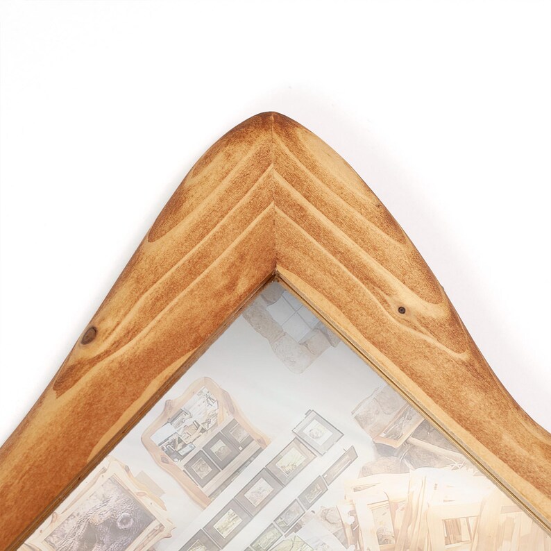 Pu&ograve; includere: Una cornice in legno marrone chiaro. La cornice presenta un design angolare a forma di V e un inserto in vetro. La cornice &egrave; progettata per contenere pi&ugrave; foto piccole. &Egrave; un oggetto decorativo.