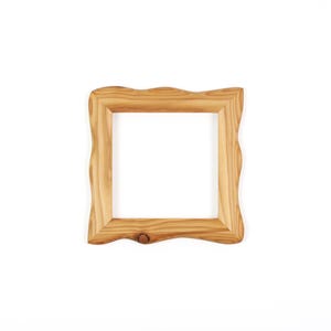 Puede incluir: Un marco de fotos cuadrado de madera en color tostado claro con patrones de veta de madera natural visibles. El marco tiene un borde exterior ondulado y org&aacute;nico distintivo y un borde interior liso, con un peque&ntilde;o nudo en la parte inferior.