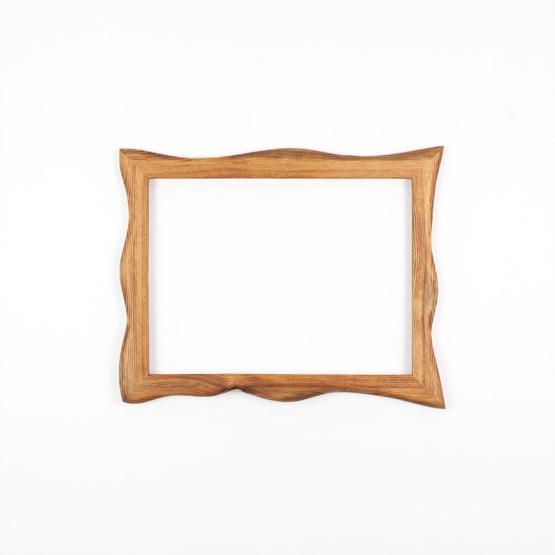 May include: A rectangular wooden picture frame with a wavy, organic edge design. The frame is made of light brown wood and has a natural finish. The frame is empty, with a white background visible through the opening.