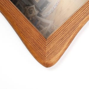 Peut inclure: Gros plan sur un cadre photo en bois avec une finition marron clair. Le cadre pr&eacute;sente un design d'angle en forme de V et une vitre. Le grain du bois est visible, ajoutant de la texture au cadre.