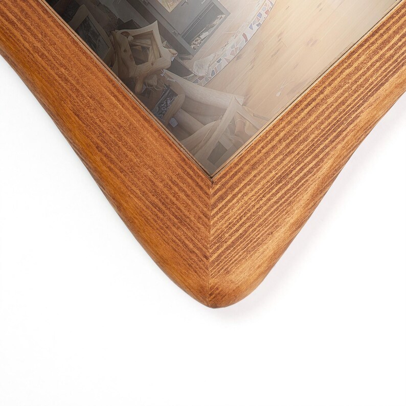 Peut inclure: Gros plan sur un cadre photo en bois avec une finition marron clair. Le cadre pr&eacute;sente un design d'angle en forme de V et une vitre. Le grain du bois est visible, ajoutant de la texture au cadre.
