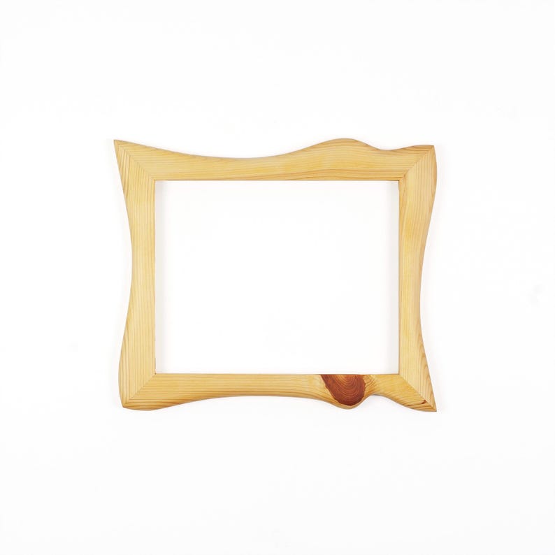 May include: A rectangular wooden picture frame with a light tan natural wood grain finish. The frame features an irregular, wavy outer edge design and a prominent dark brown circular wood knot detail on the bottom right side of the frame.