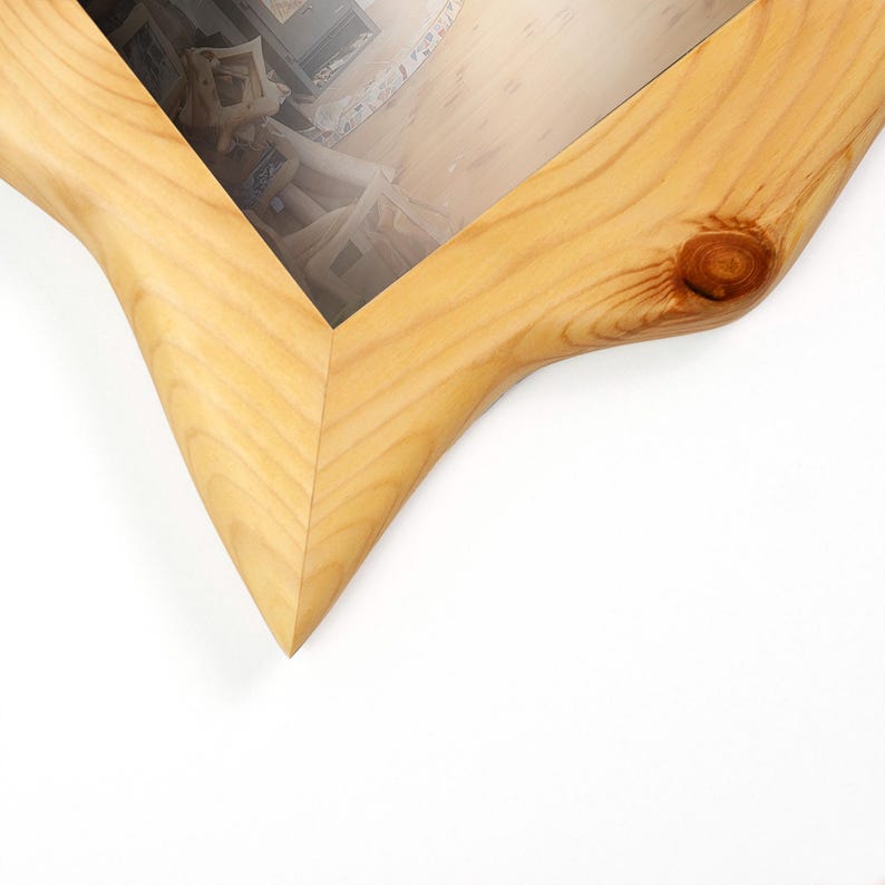 K&ouml;nnte beinhalten: Nahaufnahme eines hellen Holzfotorahmens. Der Rahmen hat eine nat&uuml;rliche Holzmaserung und ein einzigartiges, geschwungenes Design. Der Rahmen ist leer, mit einer Glasscheibe im Inneren.