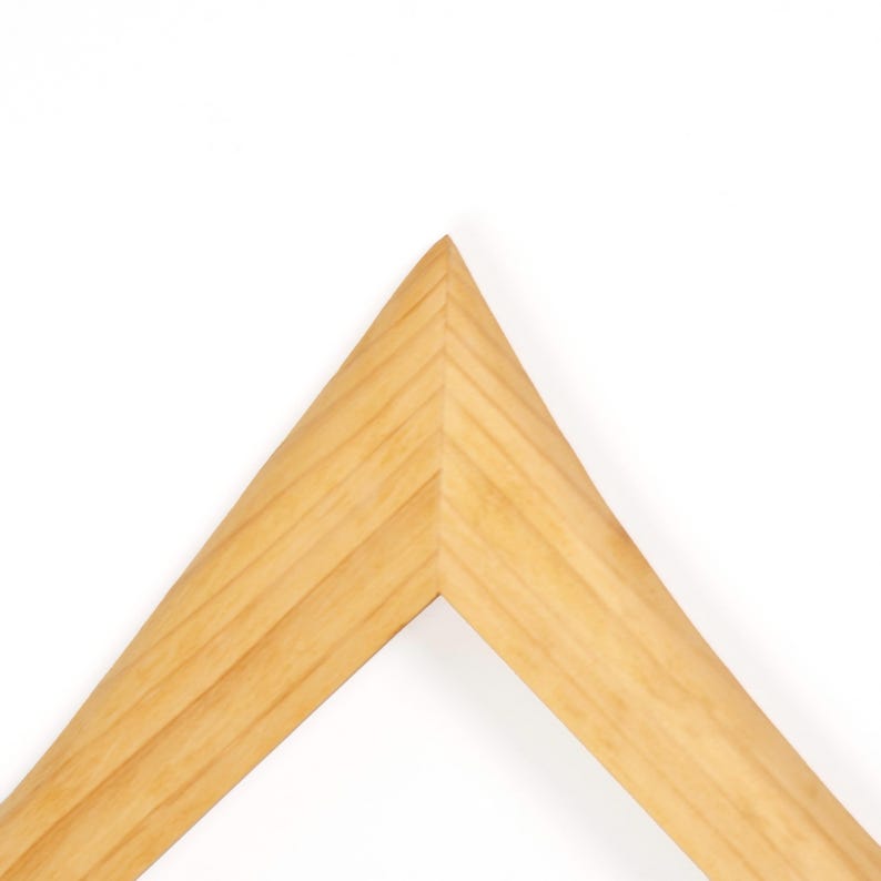 Peut inclure: Un coin de cadre photo en bois clair, mettant en valeur le grain naturel du bois. Le cadre a un design en forme de V, avec une esth&eacute;tique &eacute;pur&eacute;e et moderne. Le bois semble &ecirc;tre non fini ou l&eacute;g&egrave;rement teint&eacute;, avec une surface lisse.