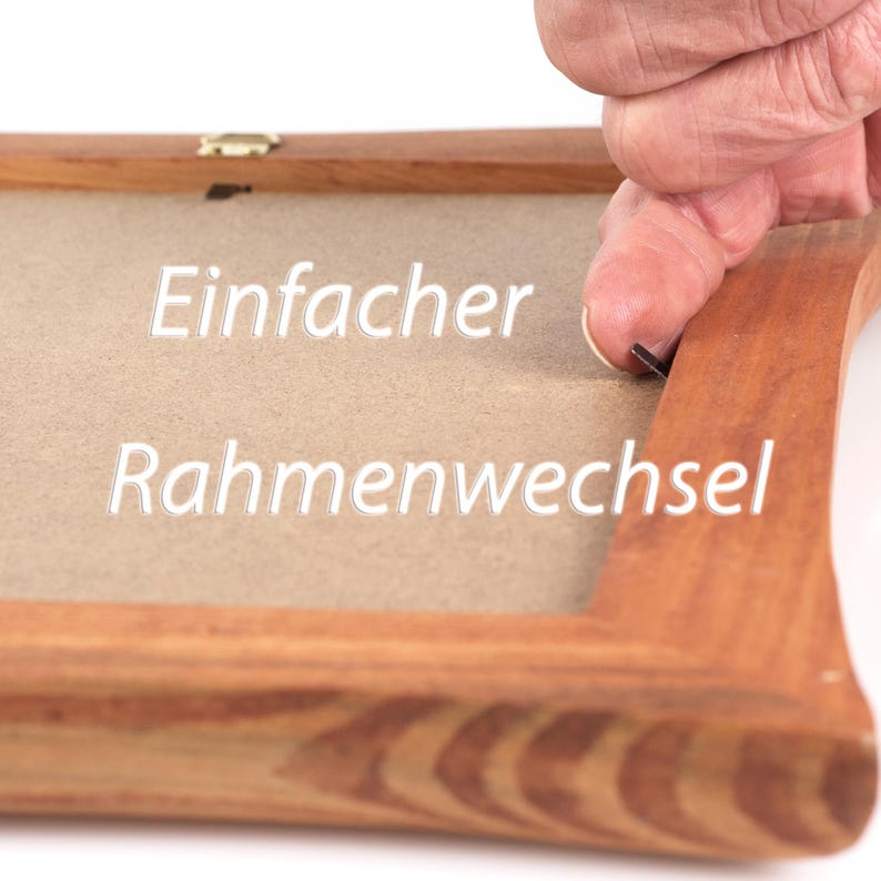 Puede incluir: Un marco de fotos de madera con acabado de veta marr&oacute;n claro, que presenta un tablero trasero de color tostado y una peque&ntilde;a leng&uuml;eta met&aacute;lica. El texto "Einfacher Rahmenwechsel" est&aacute; impreso en letras blancas en el centro del tablero.