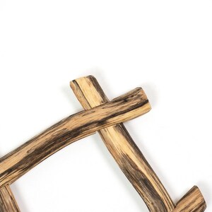 May include: A wooden frame constructed from natural, light-colored branches with prominent dark brown grain patterns and streaks. The branches are joined at an angle, creating a rustic, intersecting structure with visible wood texture.