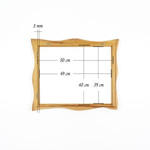 K&ouml;nnte beinhalten: Ein rechteckiger Bilderrahmen aus Holz mit gewellten oberen und unteren Kanten. Der Rahmen hat eine St&auml;rke von 5 mm. Die Au&szlig;enma&szlig;e betragen 50 cm mal 40 cm, w&auml;hrend die Innenma&szlig;e 49 cm mal 39 cm sind. An der R&uuml;ckseite befinden sich Metallaufh&auml;nger.