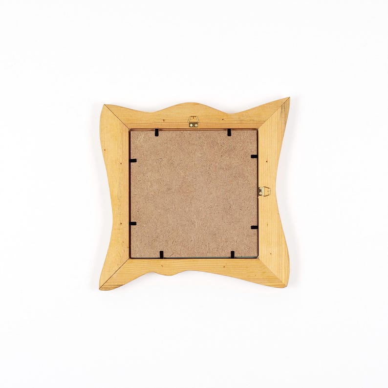Peut inclure: Dos d'un cadre photo en bois brun clair avec un design ondul&eacute; unique. Le cadre a une ouverture carr&eacute;e et un dos en carton. Le cadre est pos&eacute; sur un fond blanc.