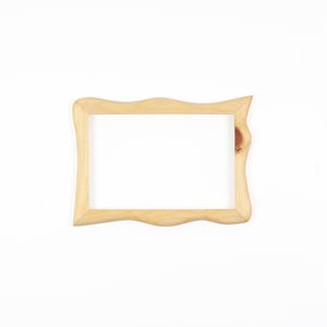 May include: A rectangular wooden picture frame with a light tan natural wood grain finish. The frame features a wavy, organic edge design along the top and bottom borders, and a visible dark wood knot detail on the right side of the frame.