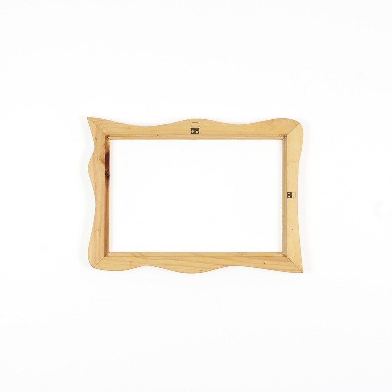 May include: A rectangular wooden picture frame with a natural light brown finish and wavy, organic edges. The frame features two small metal hanging brackets attached to the inner wooden border, allowing for horizontal or vertical wall mounting.