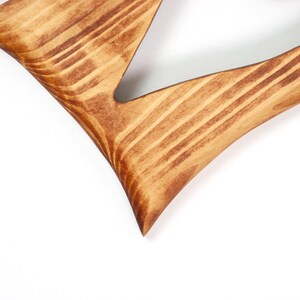 May include: Close-up of a wooden decorative letter 'V' with a natural wood grain finish. The letter is stained in shades of brown, with visible wood grain patterns. The edges are smooth and rounded.
