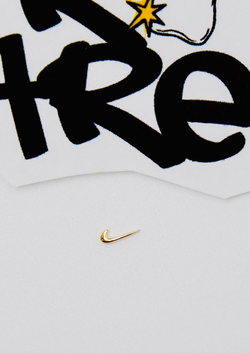 May include: A gold-colored Nike swoosh logo on a white background.