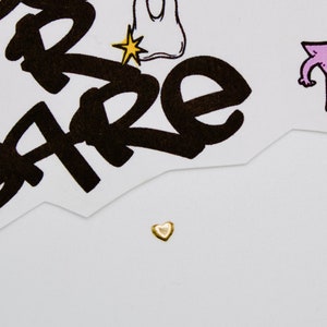 May include: A small gold heart charm on a white background.