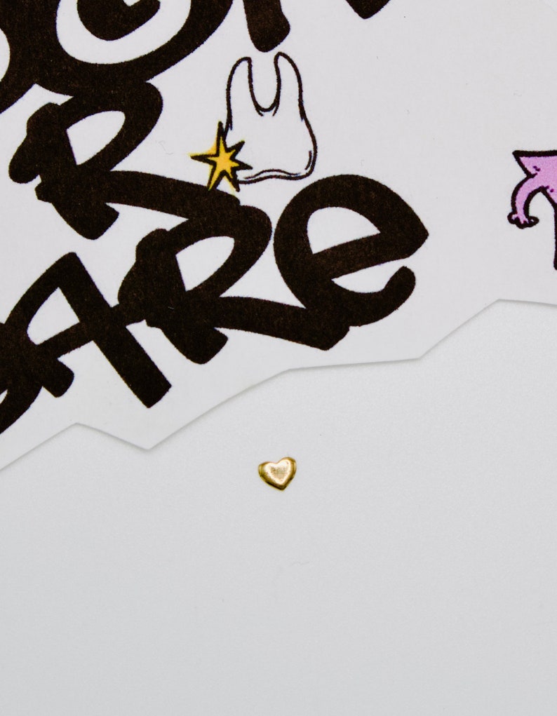 May include: A small gold heart charm on a white background.