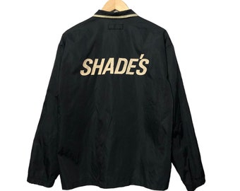 Chaqueta de nailon negra con botones, diseño de prevalencia de tonos vintage y logotipo grande.