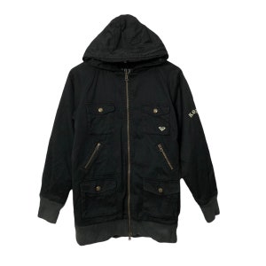 May include: Black hooded jacket with a zipper closure, four front pockets, and a ribbed hem and cuffs. The jacket features the Roxy logo on the chest and sleeve. The jacket is made of a durable fabric.