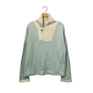 May include: A light blue long-sleeve sweatshirt with a cream-colored collar and button closure. The sweatshirt is hanging on a wooden hanger against a white background. The cuffs and hem are cream-colored.