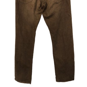 May include: A pair of brown denim jeans, viewed from the back. The jeans have a classic five-pocket design and a straight leg cut. The fabric appears to be slightly worn, giving them a vintage look. The color is a rich, earthy brown.