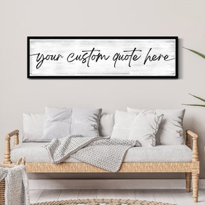 Op de afbeelding: Een zwart ingelijst bord met een witte achtergrond en de tekst "your custom quote here" geschreven in zwarte cursieve letters.