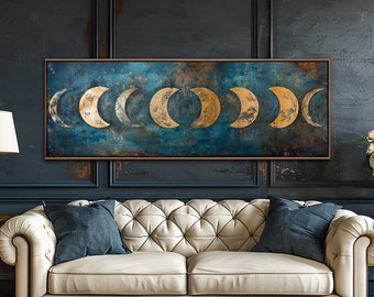 May include: A white tufted sofa with two blue pillows sits in front of a dark blue wall with a framed print of gold crescent moons on a blue background. The sofa is in a living room setting with two side tables and lamps.