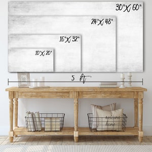 May include: A white canvas print with a wood grain texture. The print is shown in four different sizes: 10 inches by 20 inches, 16 inches by 32 inches, 24 inches by 48 inches, and 30 inches by 60 inches. The print is displayed above a wooden console table with two black wire baskets and a throw pillow with the text "welcome home".