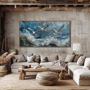 Puede incluir: Una gran pintura abstracta de tres gaviotas volando sobre un mar tormentoso. La pintura est&aacute; enmarcada en un sencillo marco de madera y cuelga de una pared de hormig&oacute;n en un sal&oacute;n. La habitaci&oacute;n cuenta con un gran sof&aacute; de esquina, una mesa de centro de madera y una alfombra tejida.