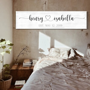 May include: White wooden sign with black calligraphy that reads "henry &hearts; isabella" and "EST. MAY 12, 2019".
