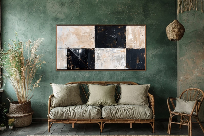 May include: Abstract painting with black and white squares on a canvas with a textured surface. The painting is hanging on a green wall in a room with a couch and a chair.