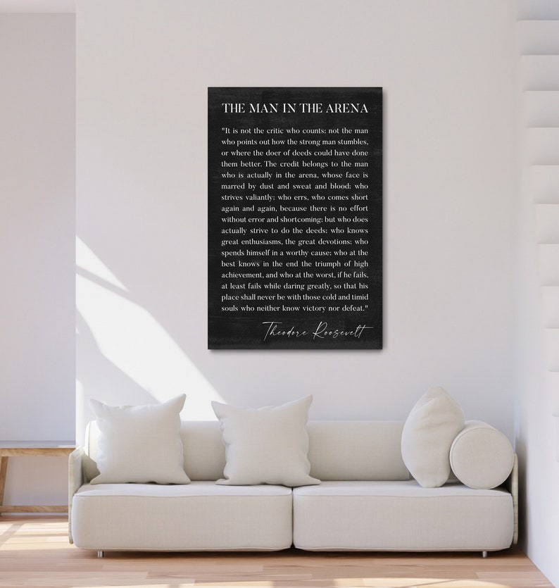 May include: Black and white typography quote on a dark background. The quote is by Theodore Roosevelt and reads "The Man in the Arena." The quote is about the importance of taking action and striving for greatness, even in the face of failure.