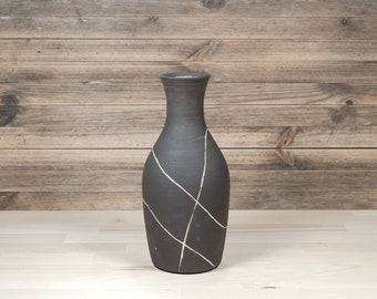 Ceramic vase from black stoneware and white lines running across the vase. Height 23 cm.
