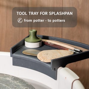 May include: A dark gray plastic tool tray for a pottery splash pan, featuring a curved edge that mounts onto the rim. The tray holds a green and white stamp, a wooden carving tool, a metal rib, and a textured sponge. Text reads: TOOL TRAY FOR SPLASHPAN K. from potter - to potters.