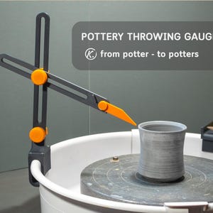 Op de afbeelding: Een pottenbakkersmal met de tekst "POTTERY THROWING GAUGE" en "from potter - to potters". De mal is zwart en oranje, gepositioneerd boven een grijze keramische beker op een pottenbakkerswiel. Een witte emmer staat op de voorgrond.