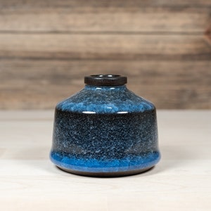 May include: A small, dark blue and black ceramic vase with a speckled glaze.