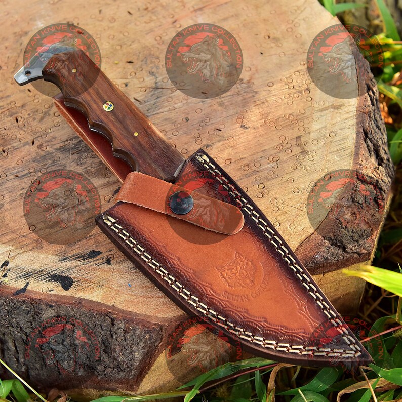 May include: A brown leather sheath with a decorative stitching pattern and a wolf design. A brown wooden handled knife with a metal blade is inside the sheath.