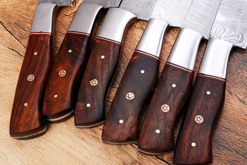 May include: A set of eight kitchen knives with dark wood handles and silver blades. The handles have a decorative pattern of small gold dots and a red and gold inlay.