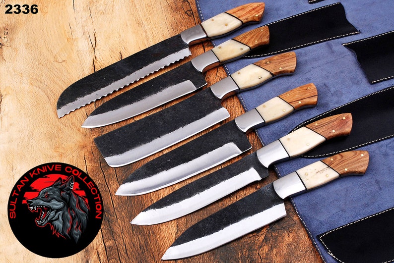 May include: Set of six black chef knives with wooden and bone handles. The knives are arranged in a row on a blue and brown surface. The knives are all different sizes and have a black blade with a polished finish. The handles are made of wood and bone and have a natural finish. The knives are labeled "Sultan Knife Collection".