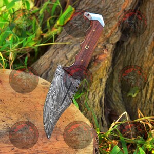 May include: A Damascus steel knife with a wooden handle. The blade has a serrated edge and a decorative pattern. The knife is resting on a wooden surface.