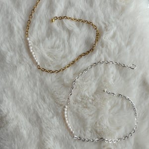 Könnte beinhalten: Zwei zarte Halsketten mit einer Reihe kleiner weißer Perlen auf einer Kette. Eine Halskette ist golden und die andere silbern.