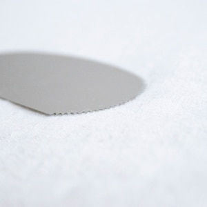 Puede incluir: Un primer plano de una herramienta de decoración de pasteles de plata con un borde festoneado.