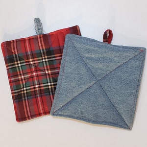 Puede incluir: Dos agarraderas para ollas, una de cuadros rojos y negros y otra de mezclilla azul. Ambas tienen un asa de bucle.