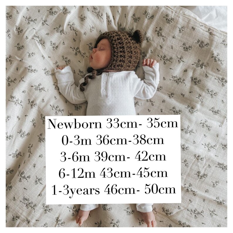 May include: A newborn baby wearing a brown crocheted bear hat and a white ribbed onesie, lying on a floral patterned blanket. The hat has small bear ears. Text on the image indicates hat sizes from newborn to 1-3 years.