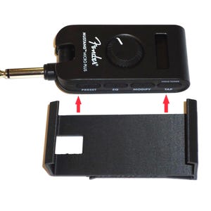 May include: Black Fender Mustang Micro Plus guitar amplifier with a black stand. The amplifier has a control knob, buttons labeled "PRESET", "EQ", "MODIFY", "TUNER", and a guitar cable input. The Fender logo is visible.
