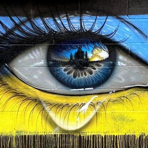 May include: A blue eye with a cityscape reflected in the pupil, painted on a brick wall. The eye is crying a single tear, with yellow and blue paint dripping down the wall, resembling the Ukrainian flag.