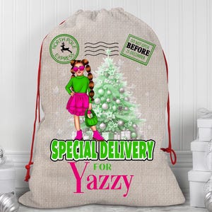 Könnte beinhalten: Ein beiger Weihnachtsgeschenksack mit roten Kordelzügen. Die Tasche zeigt eine Cartoon-Illustration eines Mädchens in einem grünen Oberteil und einem rosa Rock, einen Weihnachtsbaum und den Text "Special Delivery for Yazzy."