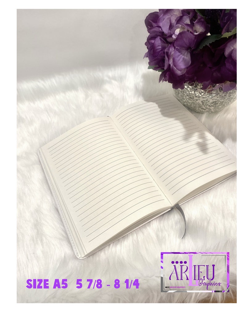 Pu&ograve; includere: Un quaderno bianco con pagine a righe, aperto per rivelare le pagine vuote. Il quaderno &egrave; su una superficie bianca e pelosa. Il testo "SIZE A5 5 7/8 - 8 1/4" &egrave; visibile nella parte inferiore dell'immagine. Un arrangiamento di fiori viola &egrave; visibile nell'angolo in alto a destra dell'immagine.