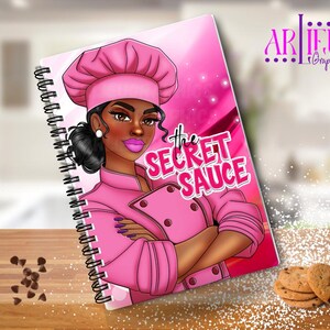 Könnte beinhalten: Ein rosa Spiralblock mit einer Cartoon-Illustration einer Frau, die einen rosa Kochhut und eine rosa Kochjacke trägt. Der Text "the SECRET SAUCE" ist in rosa und schwarzen Buchstaben auf dem Cover geschrieben.