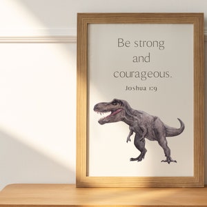 May include: A framed print with a watercolor illustration of a Tyrannosaurus Rex dinosaur. The print features the quote "Be strong and courageous." with the scripture reference "Joshua 1:9" below.