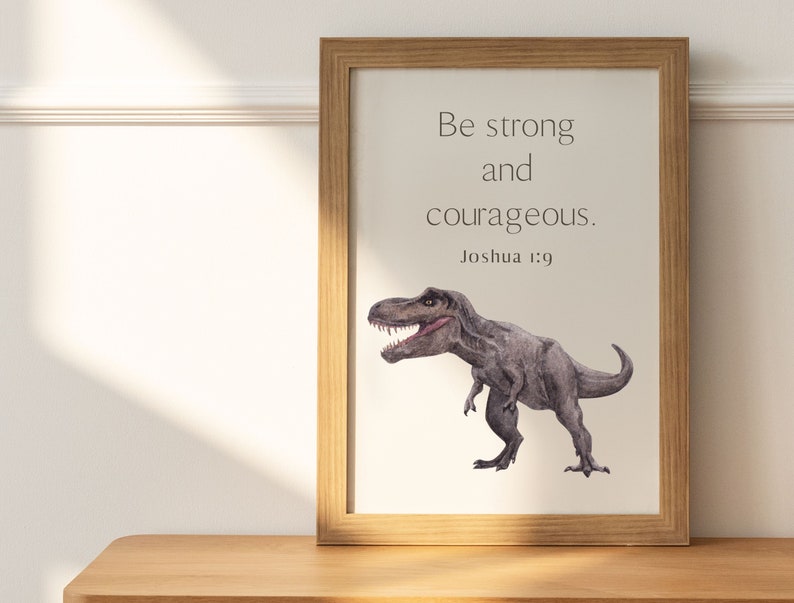May include: A framed print with a watercolor illustration of a Tyrannosaurus Rex dinosaur. The print features the quote "Be strong and courageous." with the scripture reference "Joshua 1:9" below.