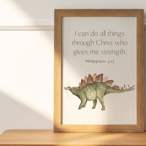 May include: A framed print with a watercolor illustration of a green dinosaur with brown spikes. The print features the quote "I can do all things through Christ who gives me strength. Philippians 4:13"